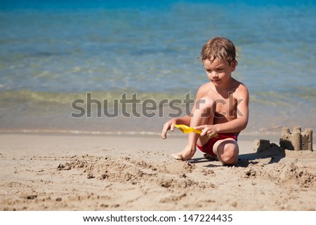 Child making sand castle on beach