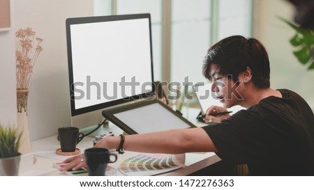 Photographer working on his project while using digital tablet in minimal style office 