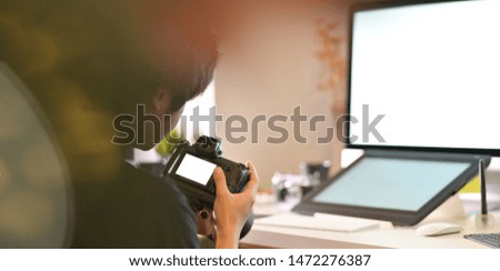 Motivated male photographer checking on his camera in his workplace 