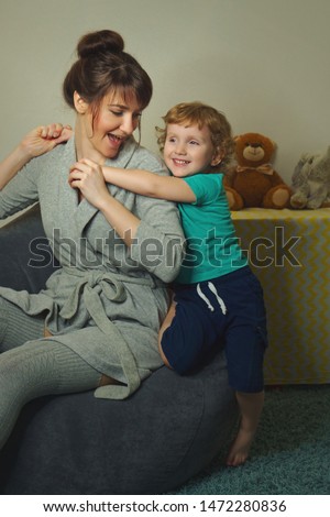 Stylish mother with a charming little son spend time in the children's room.