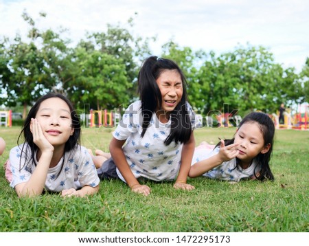 Happy Asian girls laying down on green grass outdoor together, lifestyle concept.