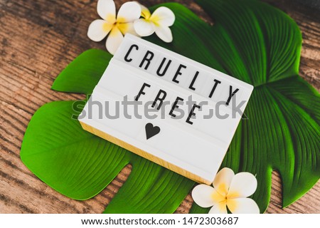 cruelty free message on lightbox with tropical settings on banana leaf and with plumeria flowers, concept of vegan products and ethics