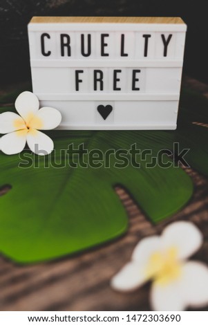 cruelty free message on lightbox with tropical settings on banana leaf and with plumeria flowers, concept of vegan products and ethics
