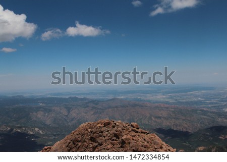 Edge of a rock cliff with the mountain ranges of Colorado in the landscape