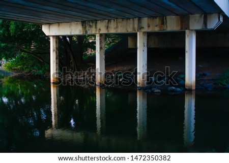 Urban setting on river bank beneath a bridge, we find symmetry, contrast and beautiful reflections.