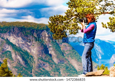 Tourist woman taking photo with camera travel picture, enjoying fjord mountains landscape. National tourist scenic route Aurlandsfjellet in Norway