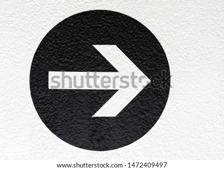 Textured wall with an arrow in a black circle pointing left.