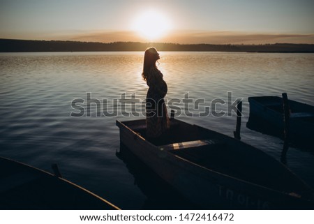 Pregnant woman posing at sunset near lake