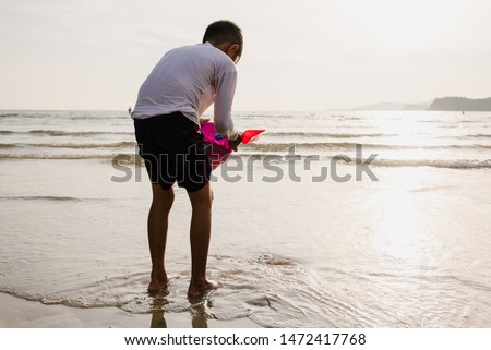 Asian boy playing bucket toy and making sand castle on the sand beach at the sea side.Happy time on travel vacation day.