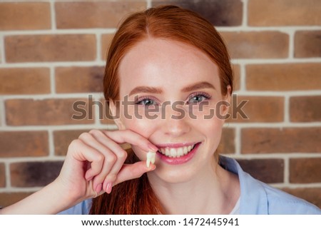 redhaired ginger female with snow-white smile holding white wisdom tooth after surgery removal of a tooth Royalty-Free Stock Photo #1472445941
