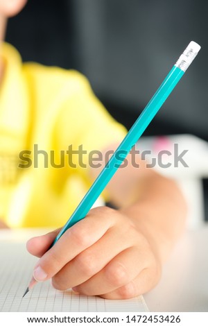 Pencil in a child's hand on a blank sheet of paper