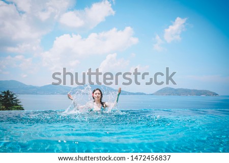 An asian woman splashing water in a swimming pool. A tourist enjoy her vacation time in Phuket, Thailand.