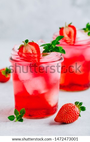 Strawberry Basil Iced Tea or lemonade in a jars on a gray stone background