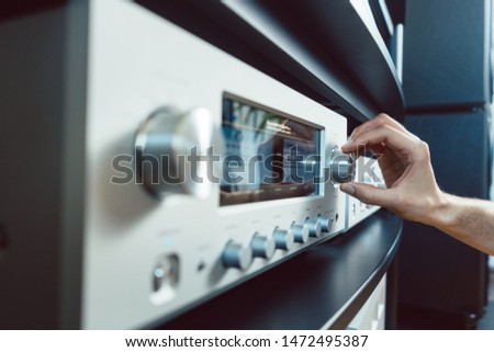 Hand of woman turning up volume of Hi-Fi amplifier in her home Royalty-Free Stock Photo #1472495387