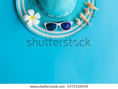 Summer   concept  setting  with  straw  hat,plumeria,sunglasses  and  colorful  seashells  on  blue  background