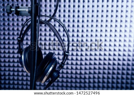 Microphone and headphone in a recording studio soundproof wall.