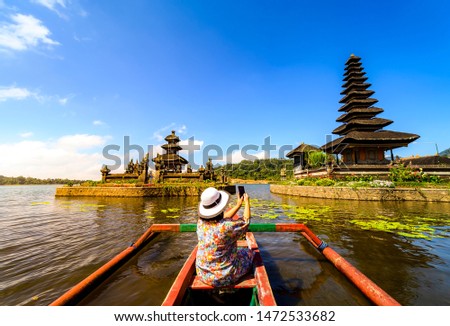 Tourists take a boat to visit and take pictures with mobile phones at Pura Ulun Danu Bratan, Bali lake. In the morning of a beautiful day