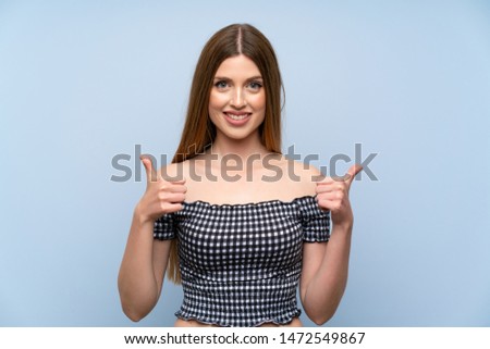Young woman over isolated blue background giving a thumbs up gesture