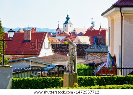 Cityscape with sculpture, house roofs and Our Lady of the Seven Sorrows Church in Old center in Slovenska Bistrica near Maribor in Slovenia. South Styria in Slovenija. Cathedral in Slovenian town.