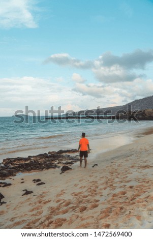 Tourist man walking along Tropical beach with turquoise ocean waves and white sand. Sand bay view. Holiday, vacation, paradise, summer vibes. Shot in Isabela, San Cristobal, Galapagos Islands.