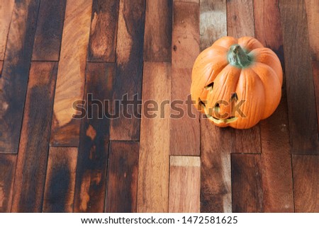 halloween, holidays and decoration concept - jack-o-lantern or carved pumpkin on wooden table at home
