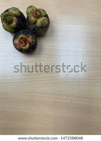 Three mangosteen on the top left and wooden table