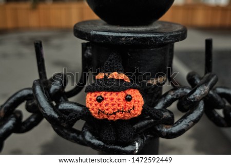 Halloween pumpkin man sits on the links of a large chain