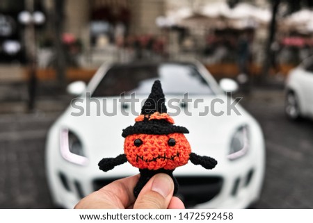 Halloween pumpkin man on the background of a sports car on the street