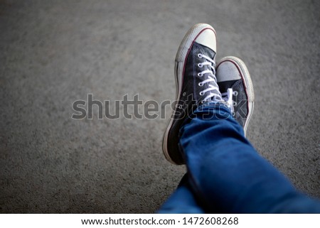 Top view of legs in jeans and sneakers on asphalt