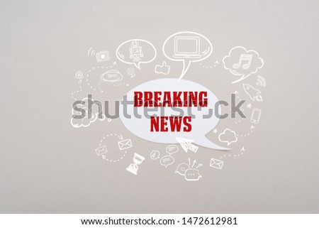 white speech bubble with red breaking news lettering and social media illustration on grey background