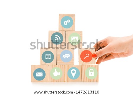 partial view of woman picking up wooden block with red magnifier sign from pyramid isolated on white