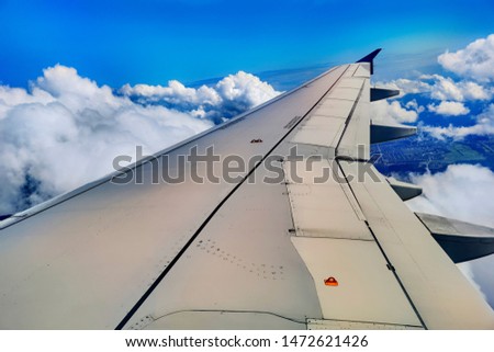 Plane wing above the clouds. A plane wing above the clouds at noon seen through a window of an aircraft, color toned travel concept picture