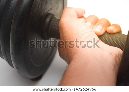 Close up a man hand is holding black dumb bell over white background. Dumb bell is an equipment of build up muscle.