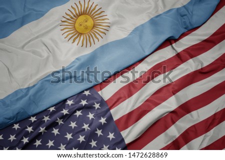 waving colorful flag of united states of america and national flag of argentina.  