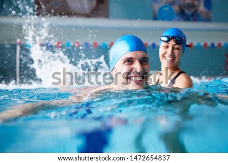 Female Swimming Teacher Giving Man One To One Lesson In Pool