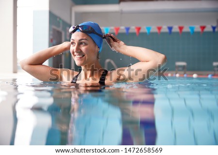 Female Swimmer Wearing Hat And Goggles Training In Swimming Pool Royalty-Free Stock Photo #1472658569