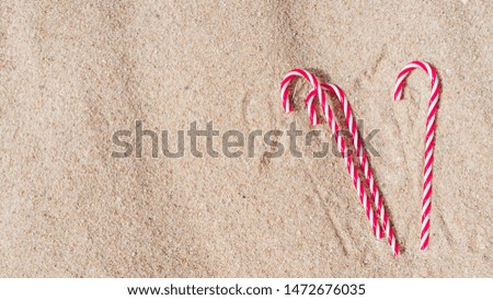 candy cane on the sandy beach. new year and xmas vacation in hot countries at sea. copy space. christmas travel.