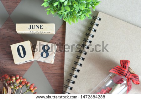 June 8. Date of June month. Number Cube with a flower, Rose bottle and notebook on Diamond wood table for the background.
