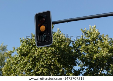 Traffic light hanging over the street with yellow light on