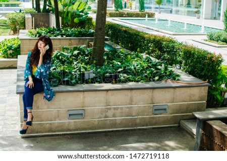 Beautiful Asian well-dressed young using cellphone
