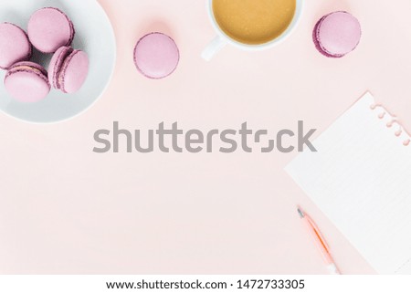 Pink background with macaroons and a Cup of tea surrounded by peonies. Top view.