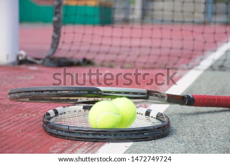 close up portrait of used tennis ball and racket on hard court