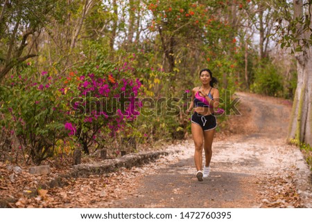 young happy attractive and exotic Asian Indonesian runner woman in jogging workout outdoors at countryside road track nature background running cheerful in healthy lifestyle concept
