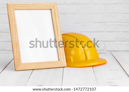 Photo frame and safety hat on white wood table with copy sapce, building concept.