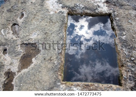 Black Sea coast of Crime.In the rock a bath in which is located sea water.Reflection of white clouds and sun