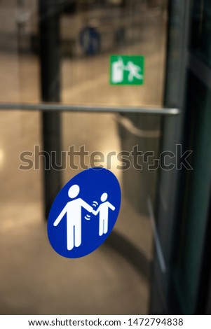 "Parent Hold Kids Hand" sign on the glass window of a revolving door, in a safety concept with space for text on top