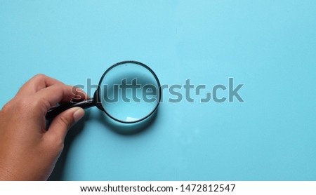 hand holding magnifying glass on the on a blue background