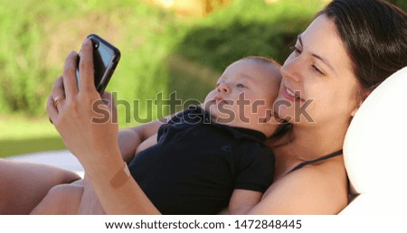 Mother taking selfie with her baby outdoors smiling posing for photo