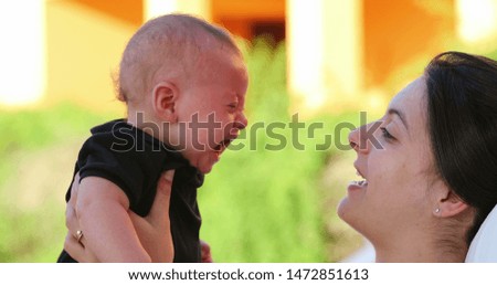 Mother kissing crying baby infant son showing love and affection outdoors