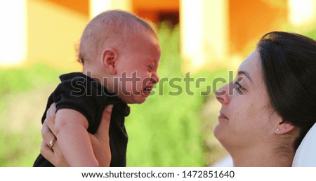 Mother kissing crying baby infant son showing love and affection outdoors